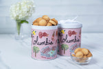 Two Columbia branded cookie tins with cookies on a light surface.